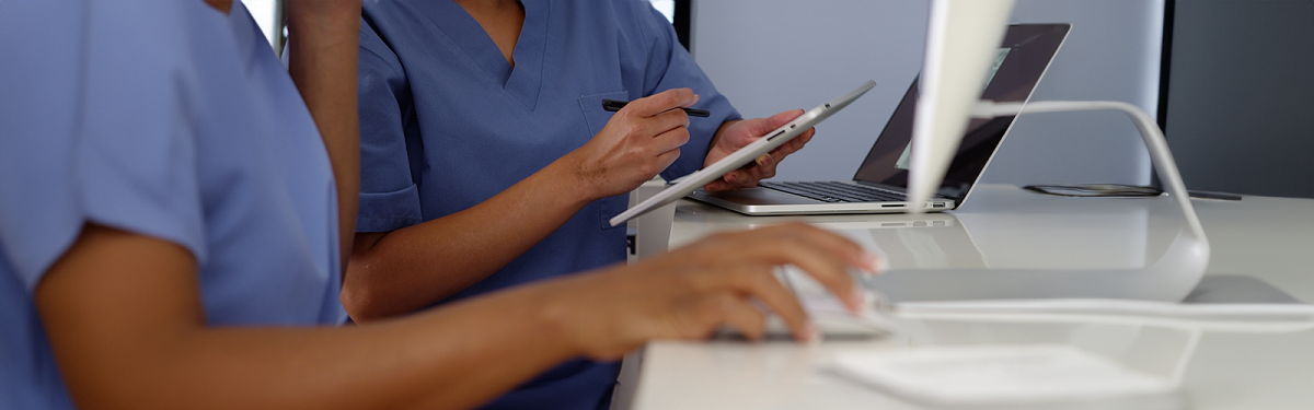 healthcare professionals standing at a desk looking at screens.