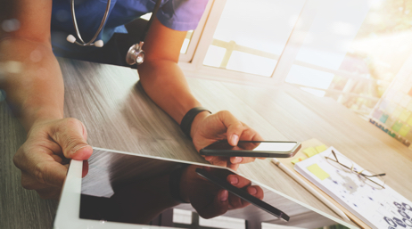 Medical professional using a tablet and smartphone.